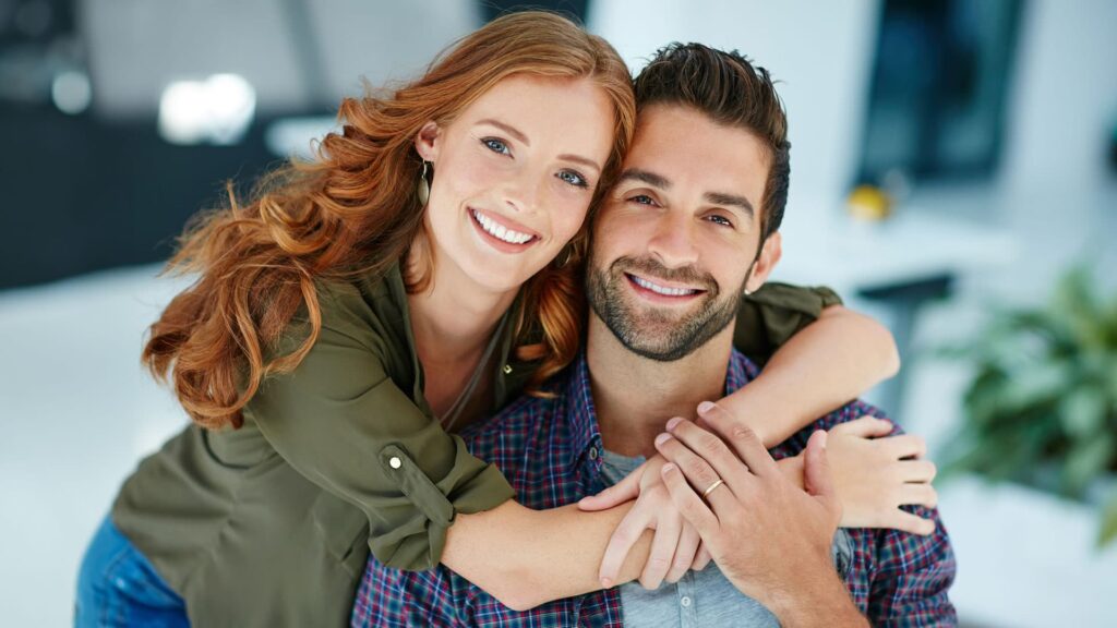 Image of male and female couple hugging and smiling at camera