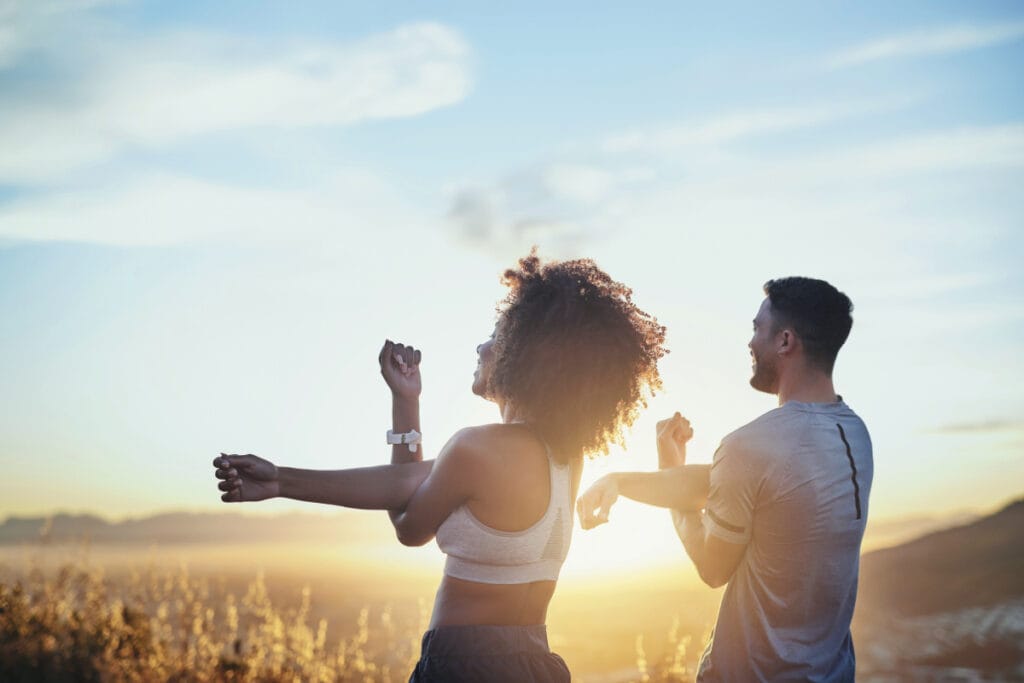 Man and woman stretching after workout as the sun rises